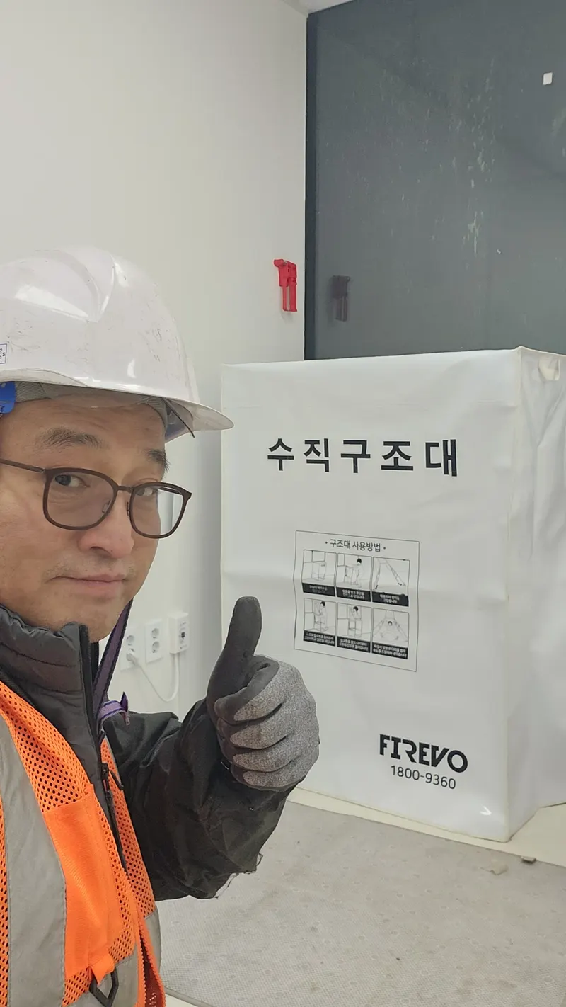고층건물 안전관리 안내 — 작업자가 수직구조대 설치 현장에서 상태를 확인하는 모습