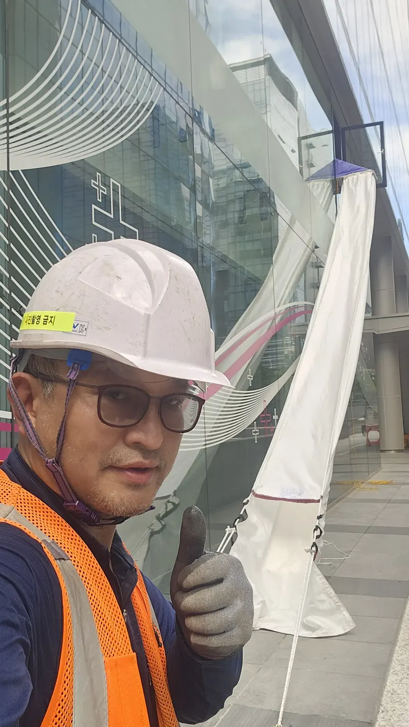 비상탈출기구 유지관리 안내 — 작업자가 수직구조대 설치 현장에서 상태를 확인하는 모습